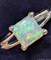 Close-up view of square opalite stone on silver split shank ring.