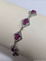 Close-up photo of the silver bracelet showcasing the linked diamond-shaped settings with ruby and cubic zirconia stones.