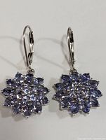 Front-facing view of both sterling silver tanzanite earrings placed side by side showing the full cluster design.
