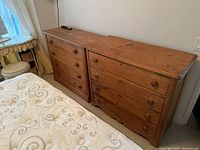 Two pine dressers side by side in bedroom beside bed