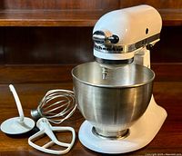 Front view of mixer assembled with bowl and three attachments laid out