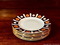 Stack of eight salad plates showing the pattern and gilded edges.