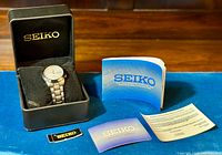 Watch in cushion inside Seiko presentation box alongside instruction booklet, guarantee card, warranty paper, hang tag