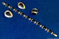 Jewelry set including tennis bracelet, earrings, and ring on blue fabric background