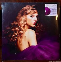 Front of sealed gatefold album cover showing portrait of Taylor Swift with long wavy hair and purple fabric, with sticker listing album details.
