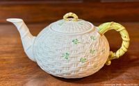 Side view of Belleek tea pot showing basket weave pattern and shamrock decoration with detailed handle and spout