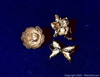 Three vintage sterling silver brooches placed on dark blue fabric showing floral, leaf and butterfly designs.