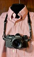 Front view of Mamiya NC1000 camera on shirt showing lens and attached strap.