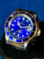 Close-up of blue dial, date magnifier, bezel markings and gold-tone hands