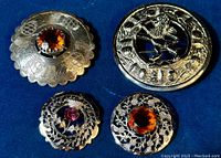 Four Celtic Scottish brooches including two with amber glass stones, one with amethyst stone, and one with horse motif