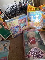 Photo showing Bright Eyes doll in original box, Build-A-Babies kit, and Let's Knit magazine with Easter collection