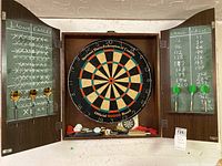 Full front view showing dartboard cabinet open, chalkboard scoring panels on each door, darts on left door and stored accessories below dartboard.