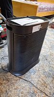 Front view of the Honeywell HPA300 air purifier showing black horizontal slat design, paperwork on top.
