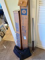 Boxed projection screens, tripod screen stand, and carrying bags on floor against wall