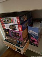 Stack of assorted jigsaw puzzle boxes including Dowdle brand and multiple 500-piece sets