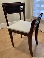 Photo showing the set from an angle displaying the chair's cushioned seat and the open shelf of the telephone table with lattice side design.