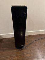 Front view of black tower air purifier showing the rectangular upright shape and control dial area.