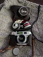 Petri rangefinder camera body with zippered leather accessory case containing two auxiliary lens attachments and lens caps