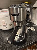 Front view of the DeLonghi espresso machine showing the brand logo, portafilter, and controls.