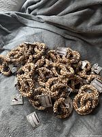 Multiple pretzel shaped dog toys made of twined natural cotton rope in tan and white lying on a grey surface.