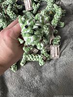 Close-up of a single green and white twisted cotton rope toy shaped like a dog held in hand, showing texture and detailing of face and limbs.