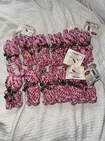 Photo of 12 pink rope bunny-shaped dog toys arranged on a white blanket, each tied with a brown polka dot ribbon and labeled.