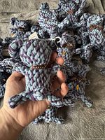 Photo showing multiple elephant shaped cotton pet toys piled together with one toy held in hand for scale.