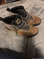 Pair of tan and beige men's hiking boots by The North Face with visible dirt and wear marks.