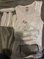 Five white Levi's undershirts, size XL, folded and with packaging, displayed on a gray surface.