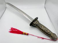 Close-up of the sword blade and detailed metal handle with red tassel attached