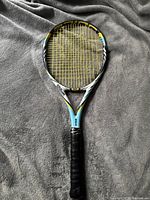 Full view of Wilson BLX Juice Pro 96 tennis racquet showing the head and handle with black grip tape and yellow strings on a gray fabric background.