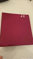 Closed maroon binder containing stamp collection.