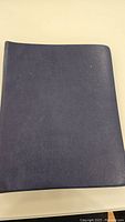 Closed view of the dark blue binder containing the stamp album.