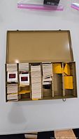 Open metal case showing stacks of vintage photo slides separated by yellow dividers.