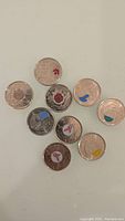 Photo showing nine Canadian commemorative quarters with colored highlights on various symbols and designs.