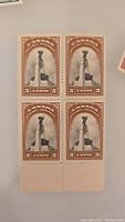 Block of four brown 2-cent Canadian stamps featuring a soldier monument and flags with perforations at the bottom edge shown