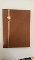 Closed Uni-Safe brown stamp book cover with gold logo