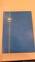 Blue Uni-Safe branded stamp book closed showing front cover with gold lettering and stripes.