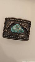 Front view of belt buckle showing turquoise stone and rope-edge border
