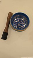 Image of the blue Tibetan singing bowl interior showing gold Tibetan characters and wooden striker.