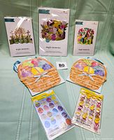 Three American Greetings Magic Moment dimensional pop-up cards in original packaging with two packages of Easter-themed American Greetings stickers laid flat in front and two Papyrus basket gift bags behind.