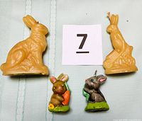 Four rabbit candles shown together; two larger beeswax candles with natural beeswax color, sitting and standing rabbits, and two smaller colorful painted wax candles.