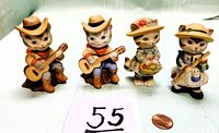 Front view of four cat figurines showing two guitar-playing cats with cowboy hats and two gardening cats with floral basket and hoe.