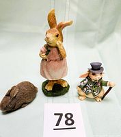 Front view of three rabbit figurines: brown rabbit, Jim Shore rabbit with top hat and cane, Greenbrier bunny in pink dress.