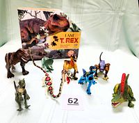 Eight dinosaur replica figures with articulated limbs posed in front of an I Am T. Rex box puzzle, showing varied colors and species.