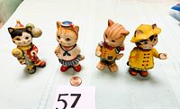 Four 3-inch Bronson cat figurines dressed in different costumes displayed with a penny for scale.