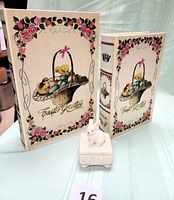 Front and side view of two fabric-covered Easter Greeting boxes of different sizes, with floral and basket of eggs/chicks design, and small ceramic bunny box in front.