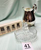 View of Gorham silver-plated water pitcher with ice guard, antique clear glass waffle block basket, and boxed set of four pewter/chrome chair-shaped place card holders