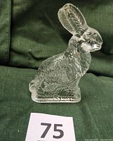 Front side view of the clear pressed glass rabbit figurine, showing upright ears and detailed surface texture.