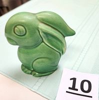Front angle showing green glazed rabbit figurine with etched eyes and smooth texture.